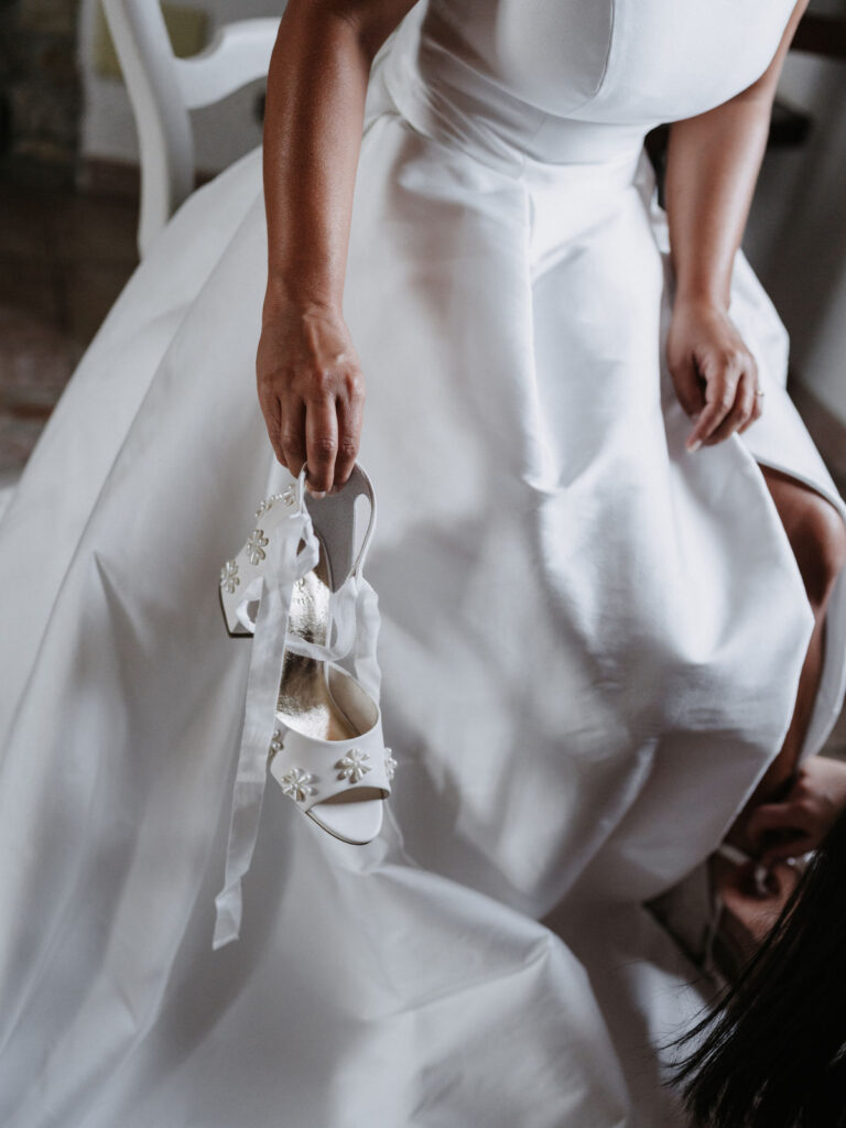 Braut im Brautkleid mit einem Schuh in der Hand